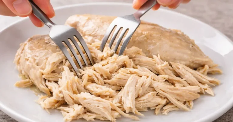 Shredded chicken breast pulled apart with forks on a white plate